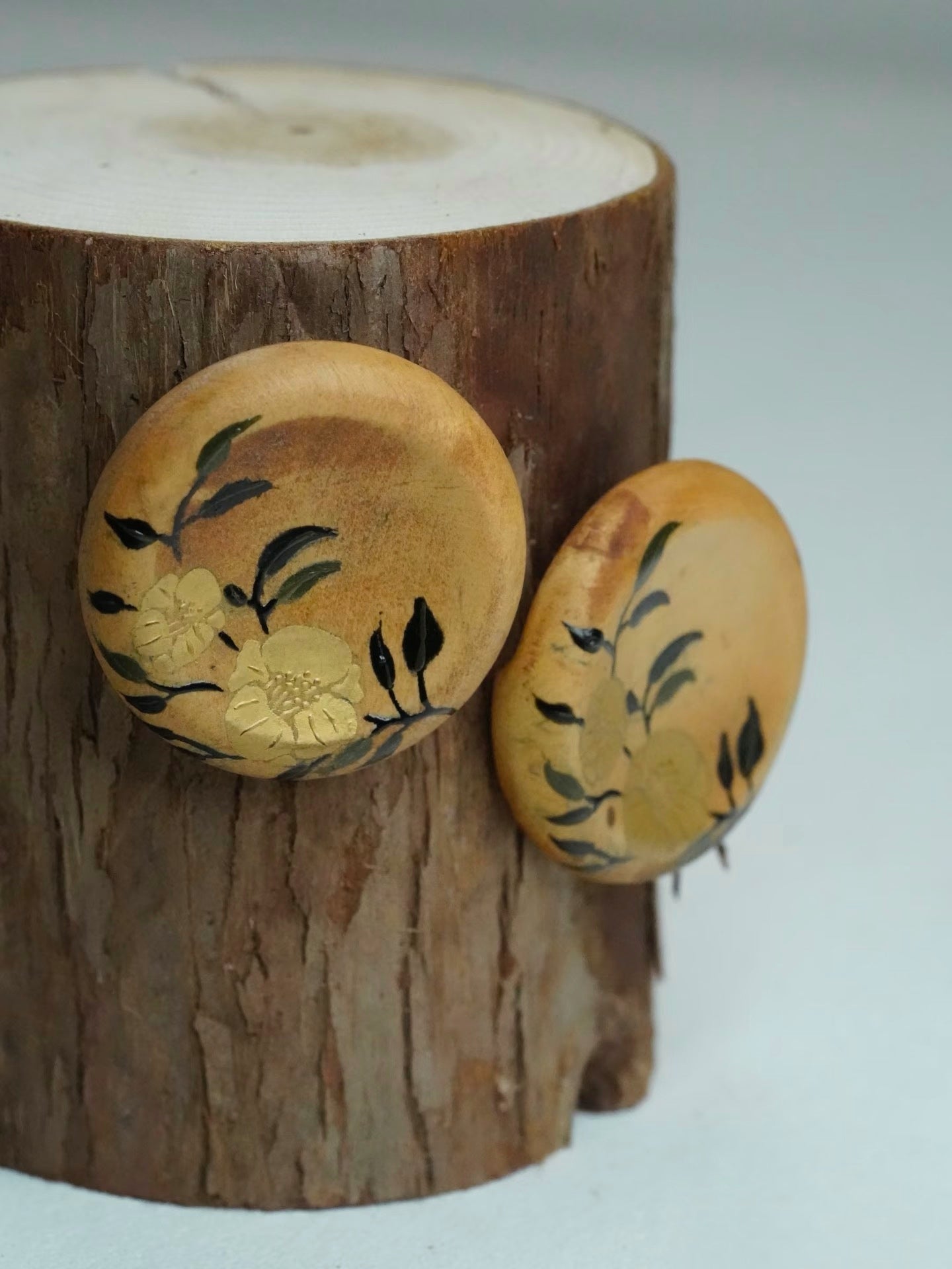 Wooden earrings with floral designs on a wooden block