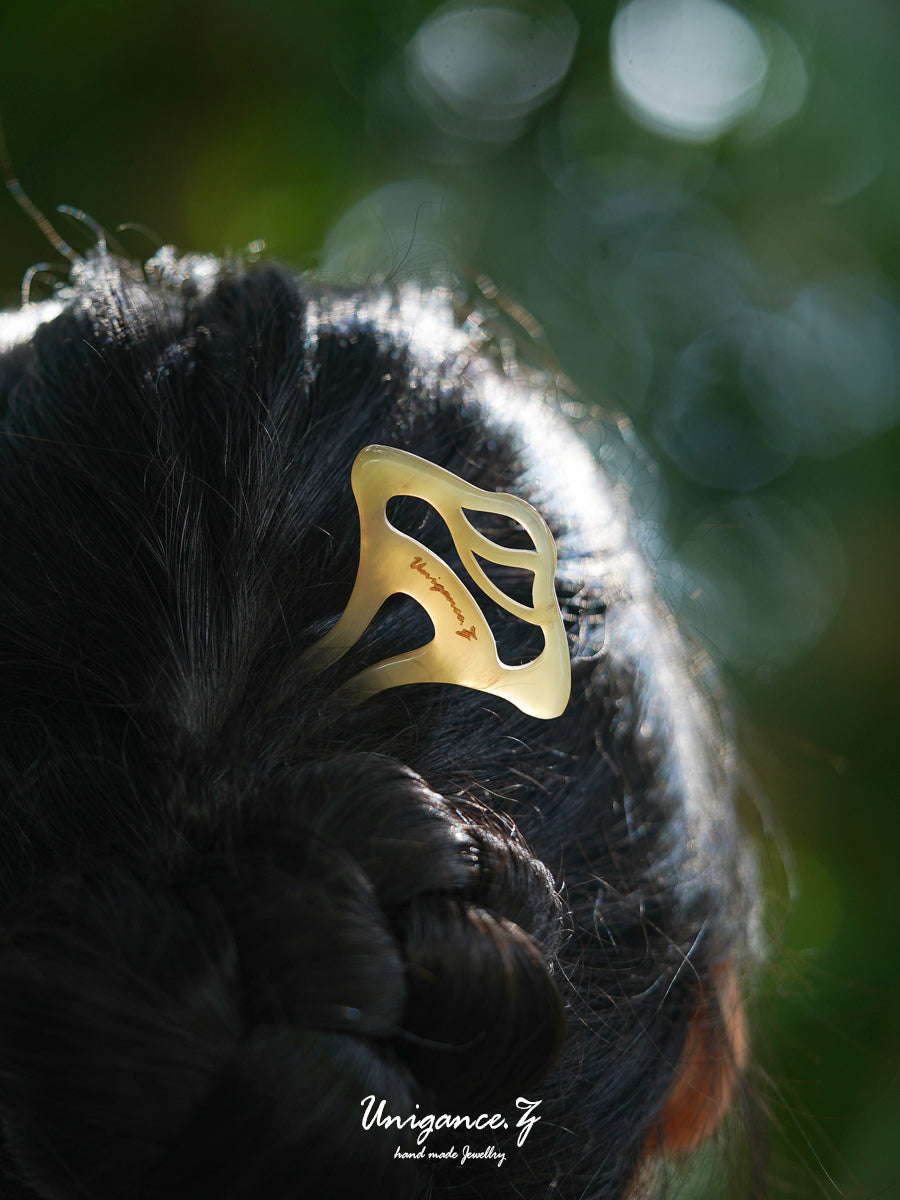 Welcoming Pine Hairpin — Gold hair clip on black hair with a blurred green background